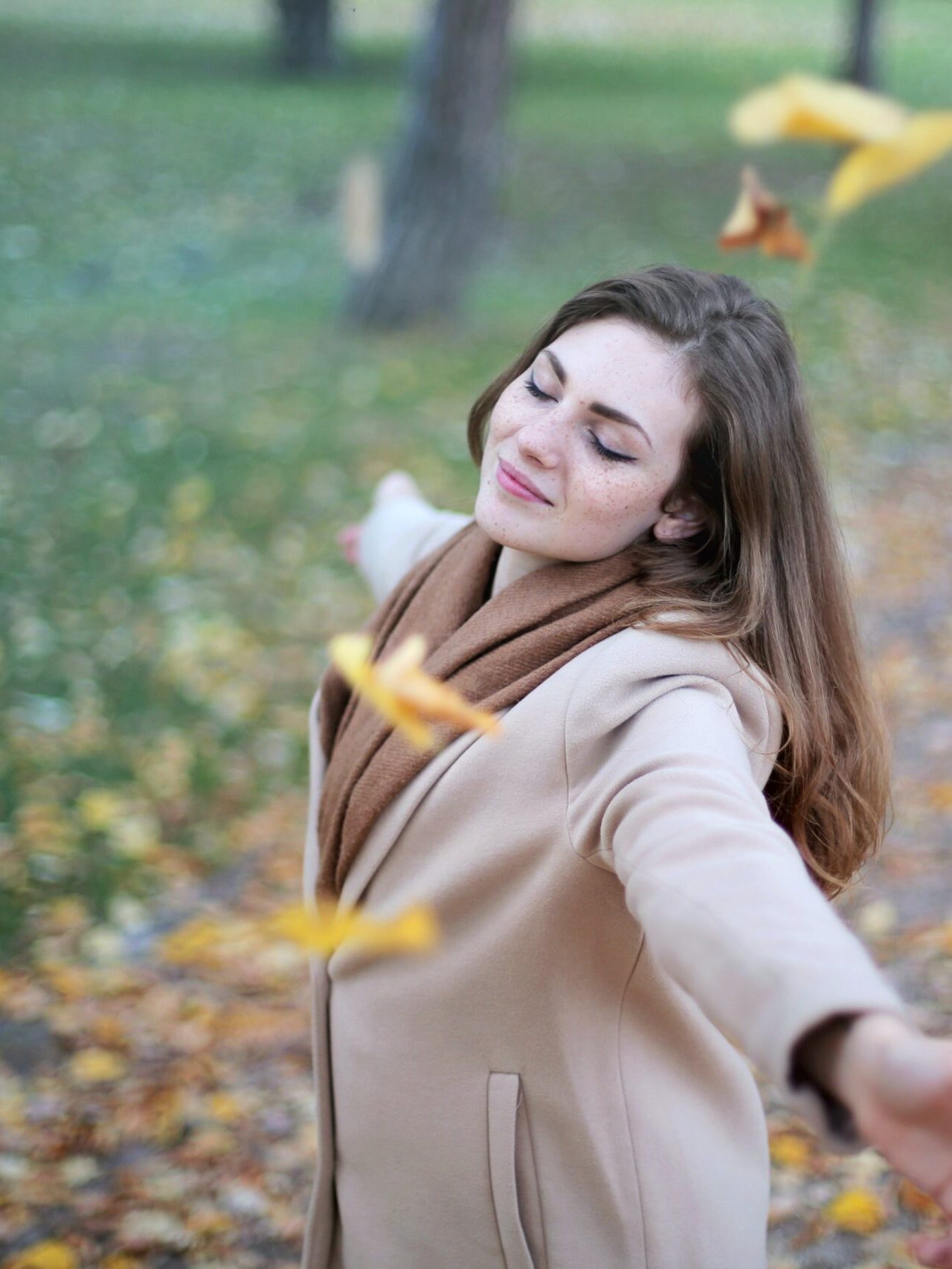 woman twirling with the leaves in a park